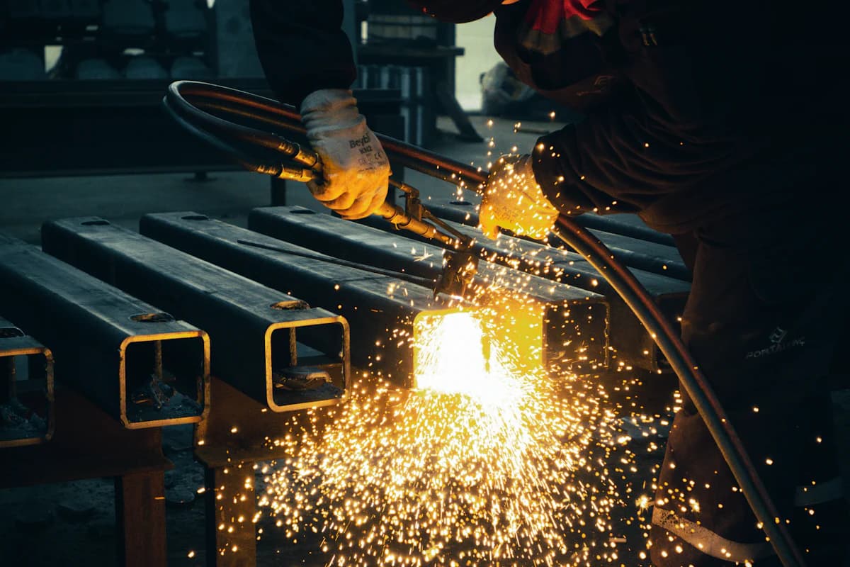 A torch cutting square steel tubing on a fabrication rack