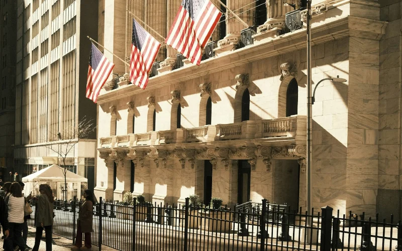 building with American flags in front on Wall street